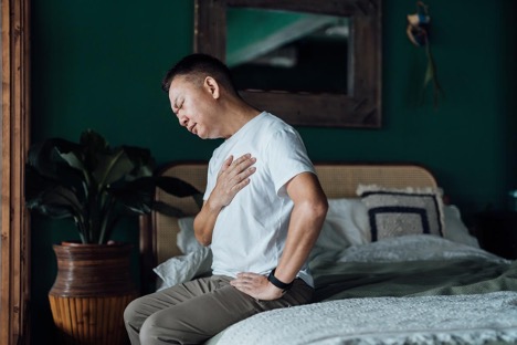man-with-eyes-closed-holding-his-chest-in-discomfort-heartburn-concept